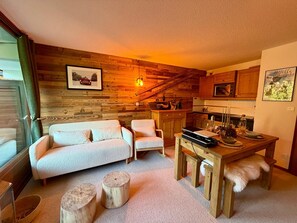 A cozy living room with a sofa, armchairs, and a dining table with a wooden bench. - Le Dahut Blanc, a charming retreat at the foot of the slopes (Morillon)