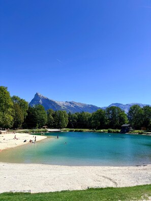 A lake with a mountain backdrop, clear skies, and a sandy beach area. - Le Dahut Blanc, a charming retreat at the foot of the slopes (Morillon)