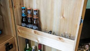 A wooden cabinet with bottles of alcoholic beverages, including Jameson whiskey and Valaisanne beer.