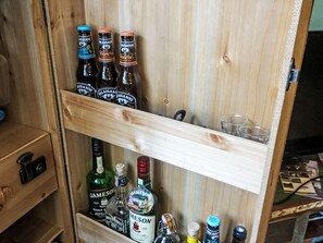 A wooden cabinet with bottles of alcoholic beverages, including Jameson whiskey and Valaisanne beer. - Ferienwohung by Interhome (Belalp-Blatten)