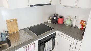 Eine moderne Küche mit Spüle, Herd und Backofen, sowie einem Toaster, Wasserkocher und Schneidebrett.