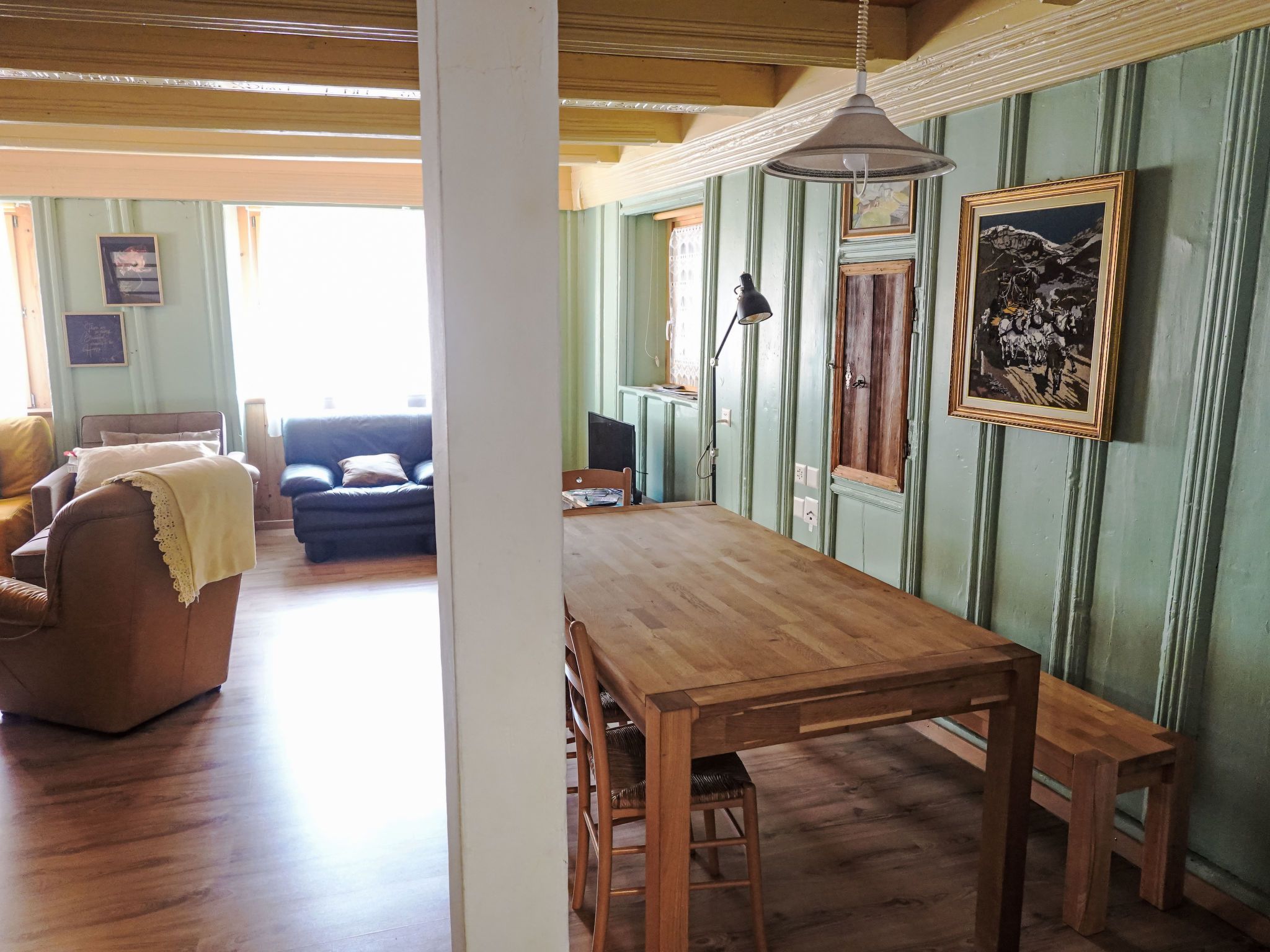 Un comedor con mesa y sillas de madera, un sofá y una ventana con vistas.