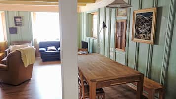 Un comedor con mesa y sillas de madera, un sofá y una ventana con vistas.