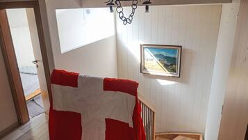 A staircase with a red and white blanket draped over it, a framed picture on the wall, and a chandelier.