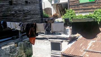Un carrer estret amb edificis de fusta, una corda de roba amb diferents peces i una reixa metàl·lica.