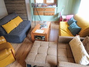 A living room with a sofa, armchair, ottoman, and a coffee table with magazines. - Ferienwohung by Interhome (Belalp-Blatten)