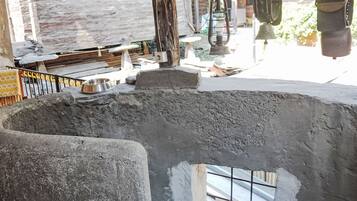 A rustic interior with a concrete structure, a metal railing, and a metal bowl on a rock.