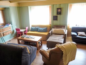 A room with a yellow sofa, a brown armchair, a small table, and a red chair. There is a window with curtains and a framed picture on the wall. - Ferienwohung by Interhome (Belalp-Blatten)