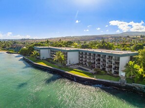 Ein Küstenhotel mit mehreren Balkonen, einem Pool und Meerblick.