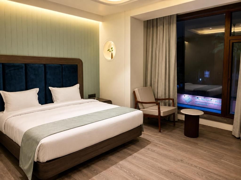 Une chambre d’hôtel avec un grand lit, une chaise, une petite table et un écran de télévision.