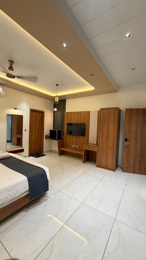 A modern bedroom with a bed, a TV, wooden wardrobes, and a ceiling fan. - The Premier Girtara Resort (Talala)
