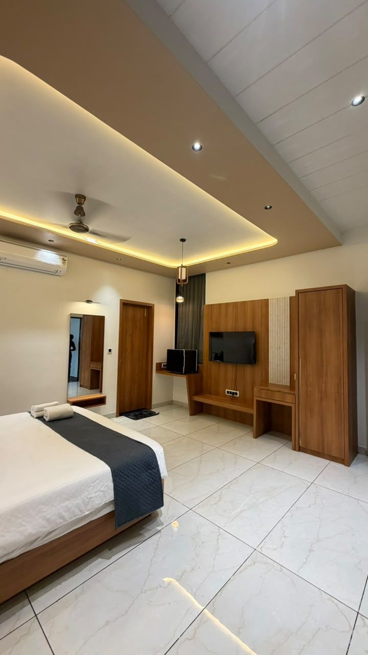 Ein modernes Hotelzimmer mit Bett, Sitzecke, Fernseher und Kleiderschrank.