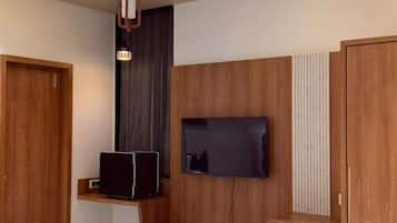Un dormitorio moderno con una cama, un televisor instalado en la pared y un banco de madera.