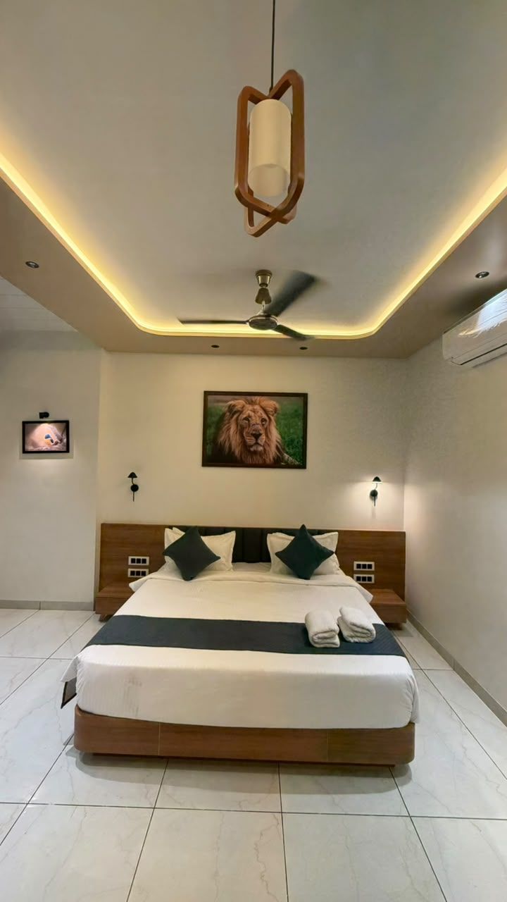 Ein modernes Schlafzimmer mit einem großen Bett, einem Deckenventilator, einem aufgehängten Bild und einer Wandleuchte.