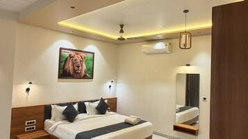 A modern bedroom with a large bed, a ceiling fan, recessed lighting, a mounted picture, and a mirror.
