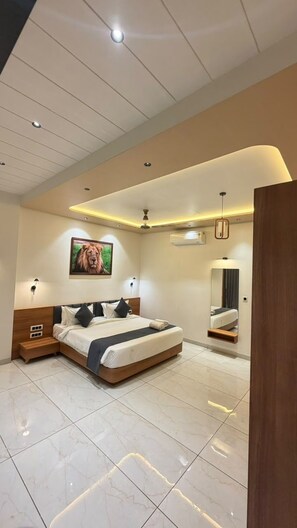 A modern bedroom with a large bed, a ceiling fan, recessed lighting, a mounted picture, and a mirror.