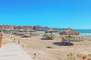 A beachside resort with sun loungers, thatched umbrellas, and a view of the ocean. - Sonoran Star 1106-02 – Seaside Ocean View Paradise (Puerto Peñasco)