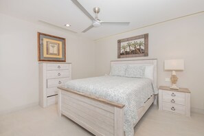 A bedroom with a bed, a nightstand, a dresser, a ceiling fan, and two wall-mounted pictures. - Sonoran Star 1106-02 – Seaside Ocean View Paradise (Puerto Peñasco)