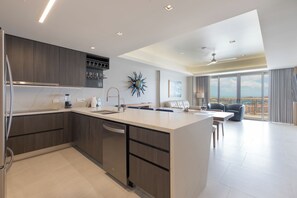 A modern kitchen with a central island, built-in appliances, and a dining area with a view. - Sonoran Star 1106-02 – Seaside Ocean View Paradise (Puerto Peñasco)