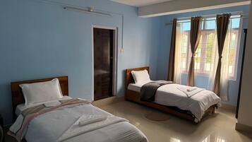 Una habitación con dos camas, una puerta y una ventana con cortinas.