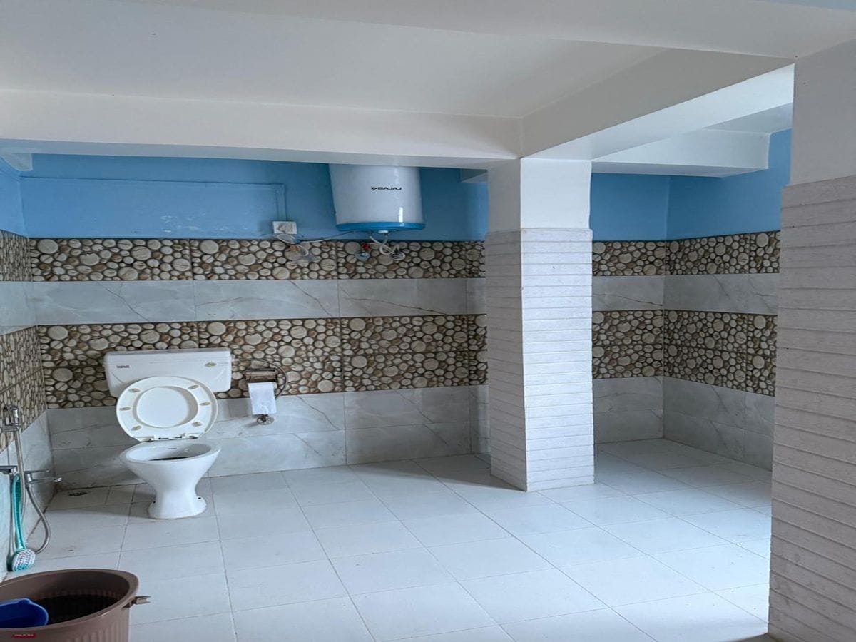 A bathroom with a toilet, a shower area, and a stone-patterned wall.