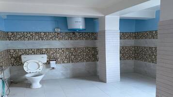 A bathroom with a toilet, a shower area, and a stone-patterned wall.
