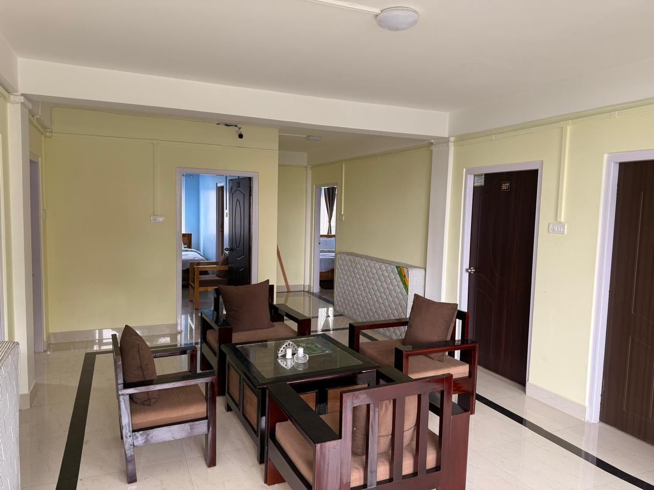 Amplia sala de estar con una mesa de centro de vidrio, sillas de madera y un sofá.