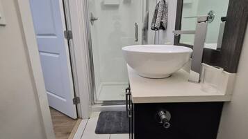 A bathroom with a white sink, a mirror, and a shower area.