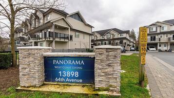A residential area with a sign for Panorama West Coast Living at 13898 64th Avenue.