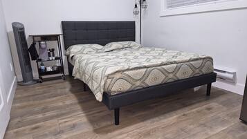 A bedroom with a bed, a bedside table, a heater, and a floor lamp.