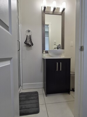 Un bagno con un lavandino bianco, mobili scuri, uno specchio illuminato e un porta asciugamani.