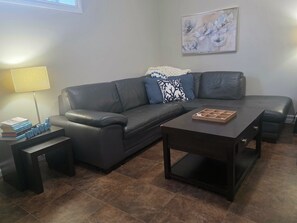 A modern living room with a leather sofa, a coffee table, a floor lamp, and a painting on the wall. - The Bluebird Inn (Fort McMurray)