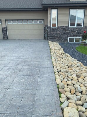 A residential driveway with a stone border and a garage door.