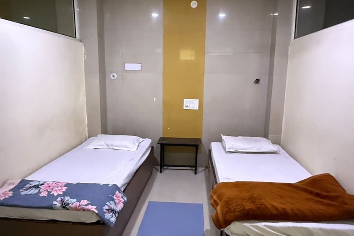 A room with two single beds, a ceiling fan, and a small table.