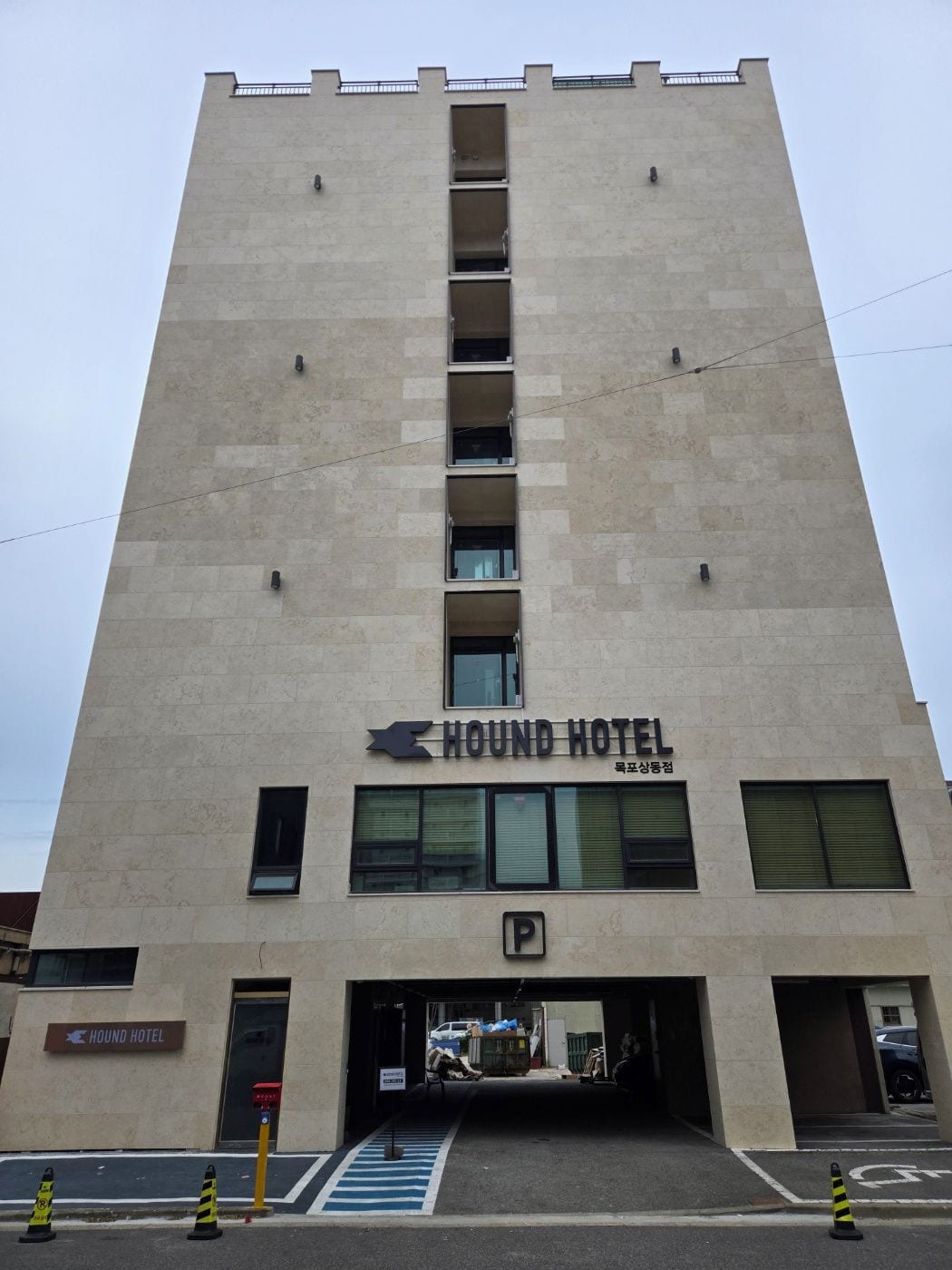 A HOUND HOTEL with a modern architectural design, featuring a prominent entrance and a parking area.