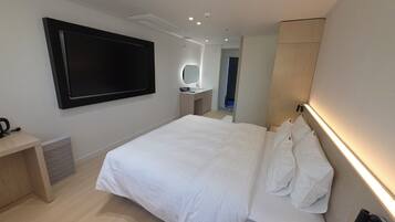 A modern hotel room with a large bed, bedside table, and a TV mounted on the wall.