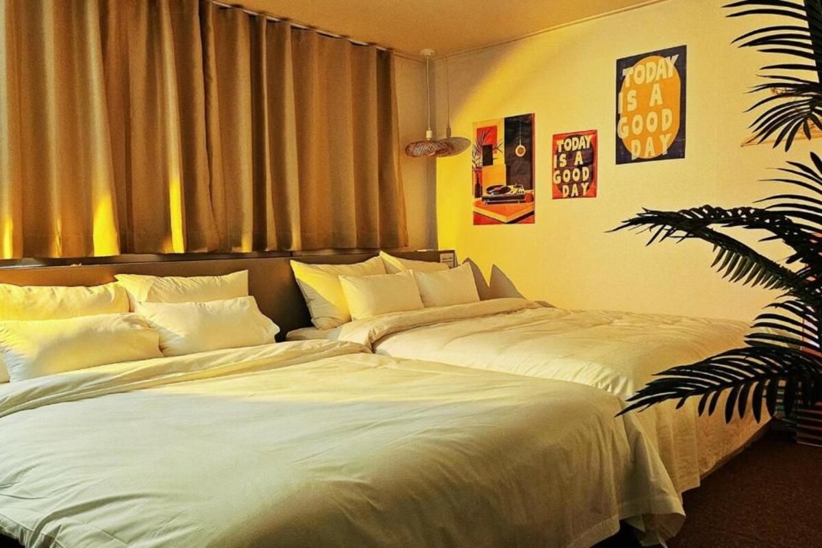 Een hotelkamer met een groot bed, gordijnen, een wandklok en inspirerende posters.