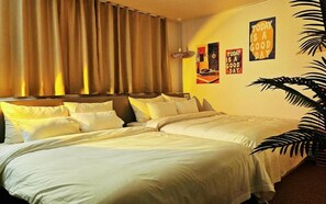 Een hotelkamer met een groot bed, gordijnen, een wandklok en inspirerende posters.