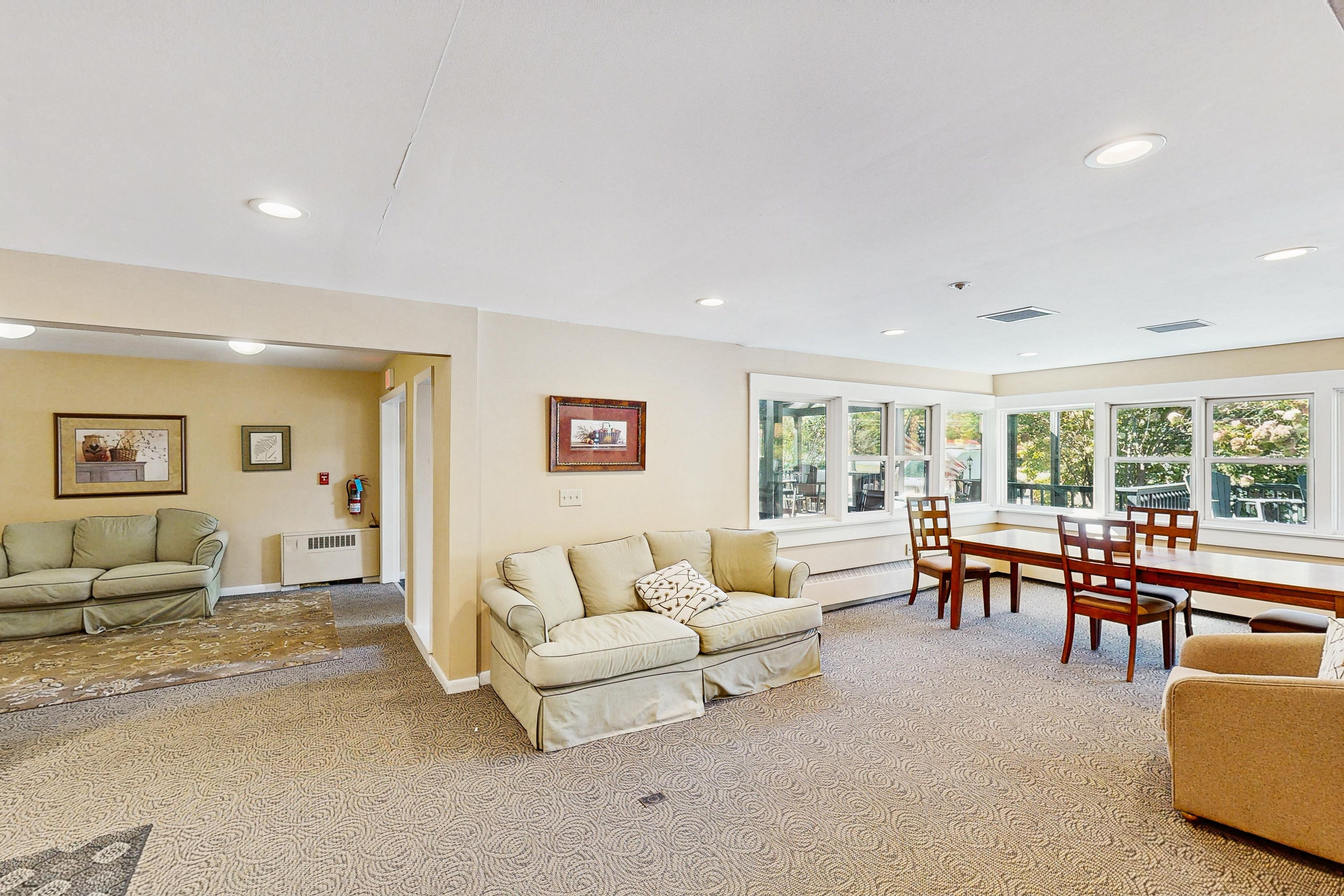 A spacious living area with a sofa, a dining table with chairs, and a fireplace.
