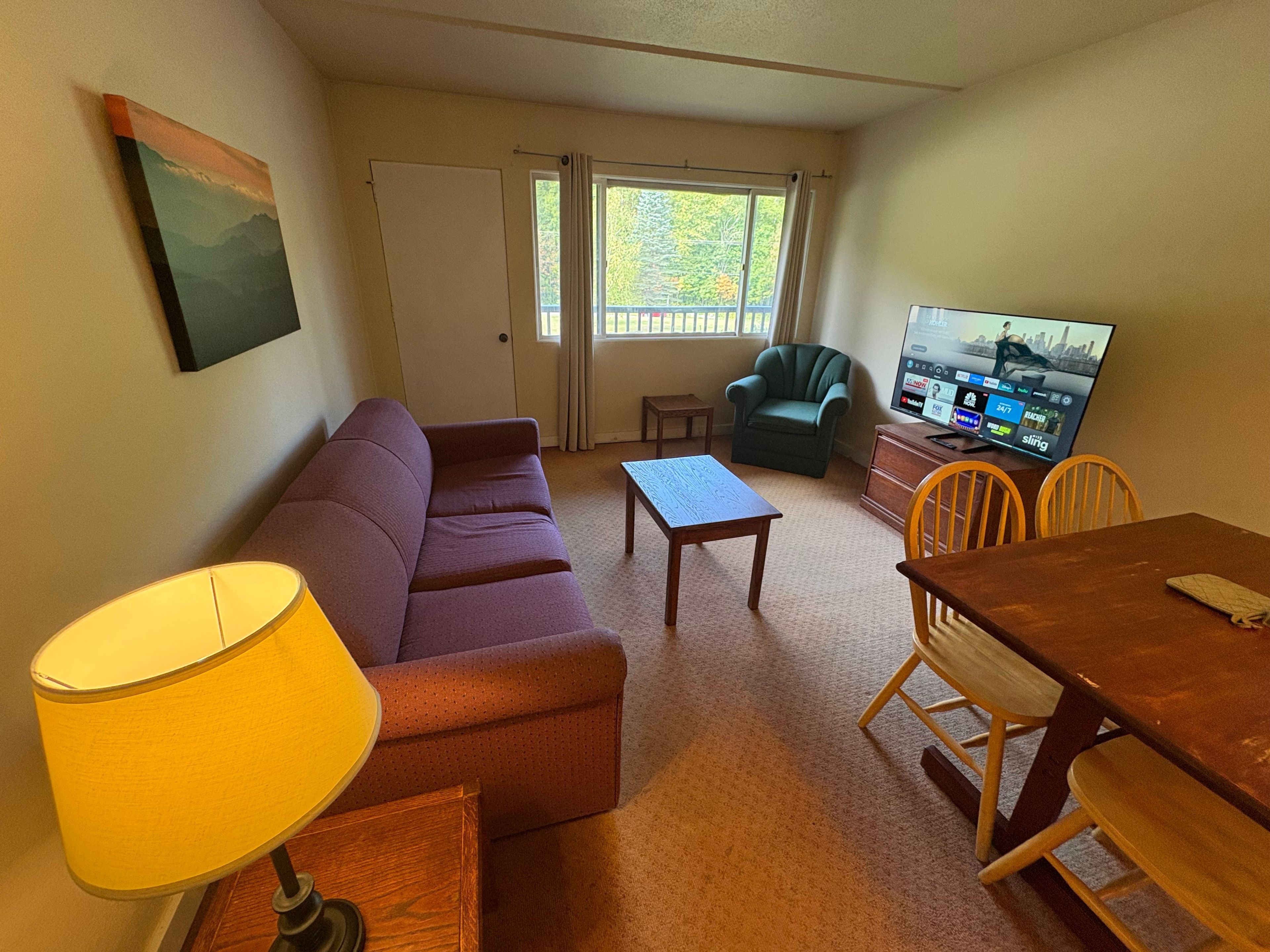 A living room with a sofa, a coffee table, a TV, and a lamp.