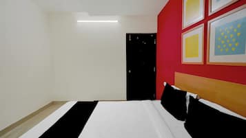 A hotel room with a bed, a door, and a wall with framed pictures.