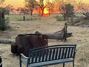 Un banco en un campo con un atardecer de fondo.