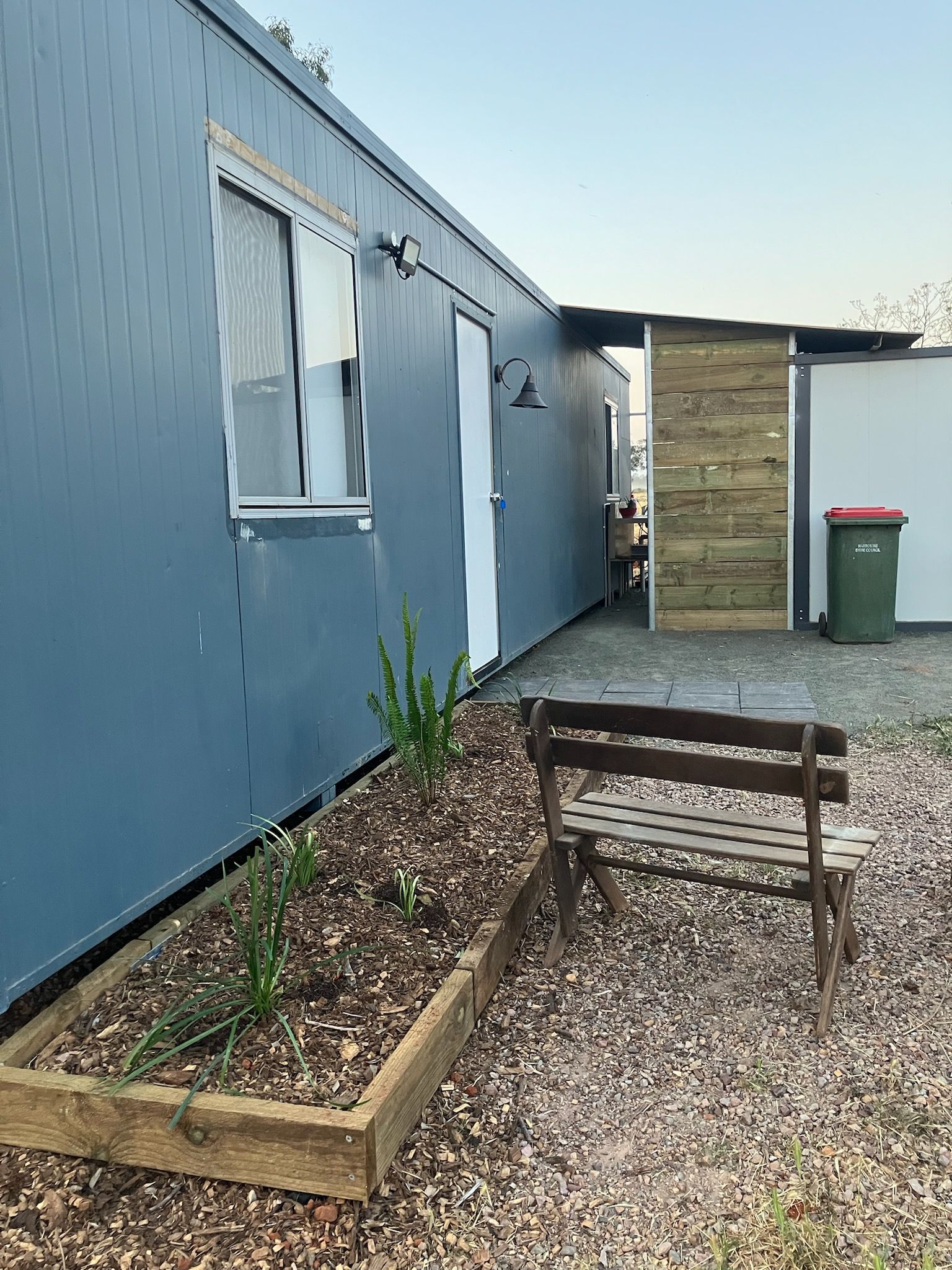 A building with a window, a bench, and a wooden fence.