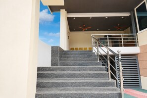 A staircase with a metal railing leading to a landing with a glass door. - Hotel O IT Hub Khammam (Khammam)
