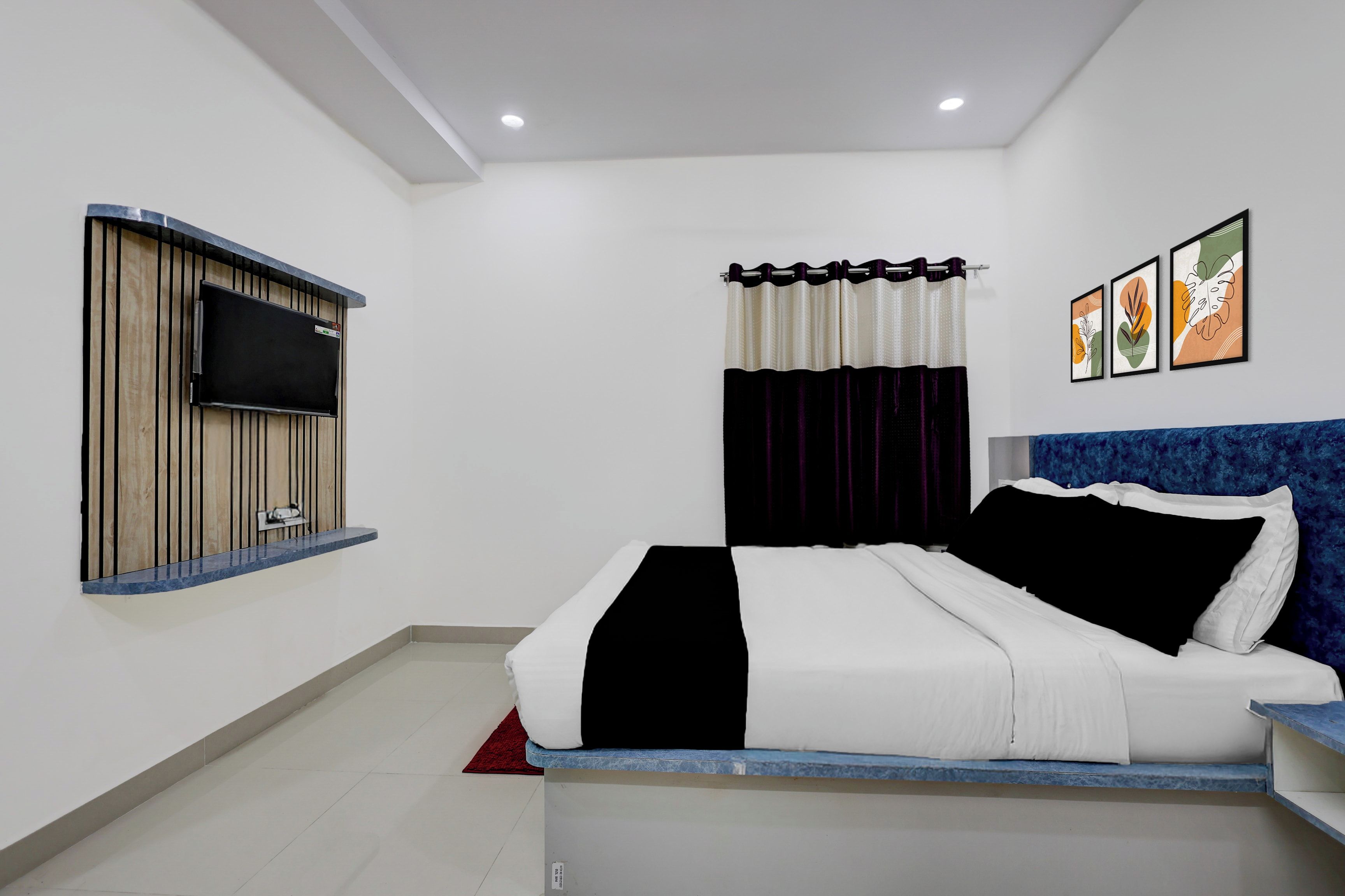 Un dormitorio moderno con cama, televisor montado y obra de arte en la pared.