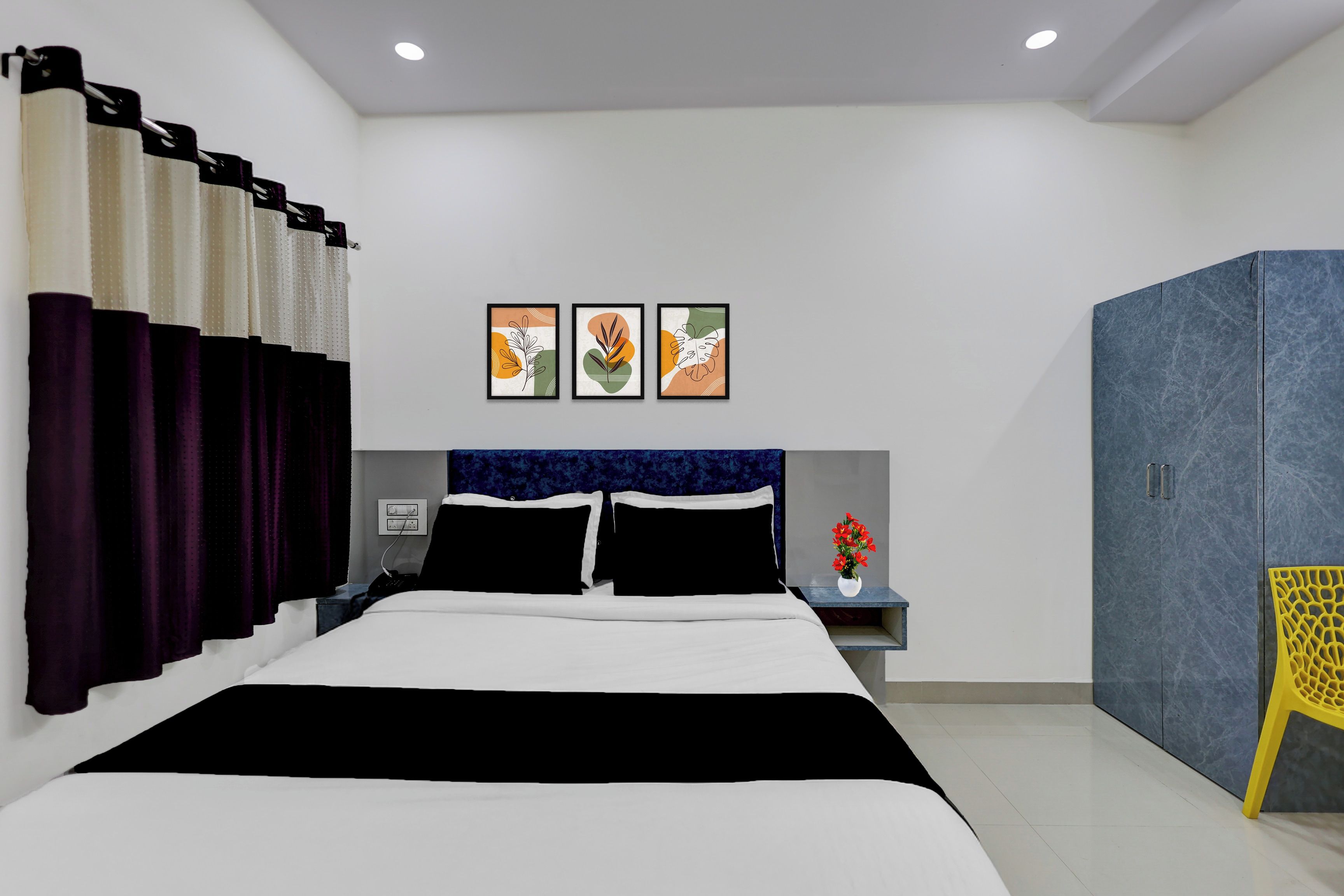 Una camera d'albergo moderna con un letto grande, un comodino, un armadio e tre quadri appesi al muro.