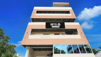Een hotel met meerdere verdiepingen, modern van ontwerp, met een opvallend 'HOTEL'-bord op de gevel.