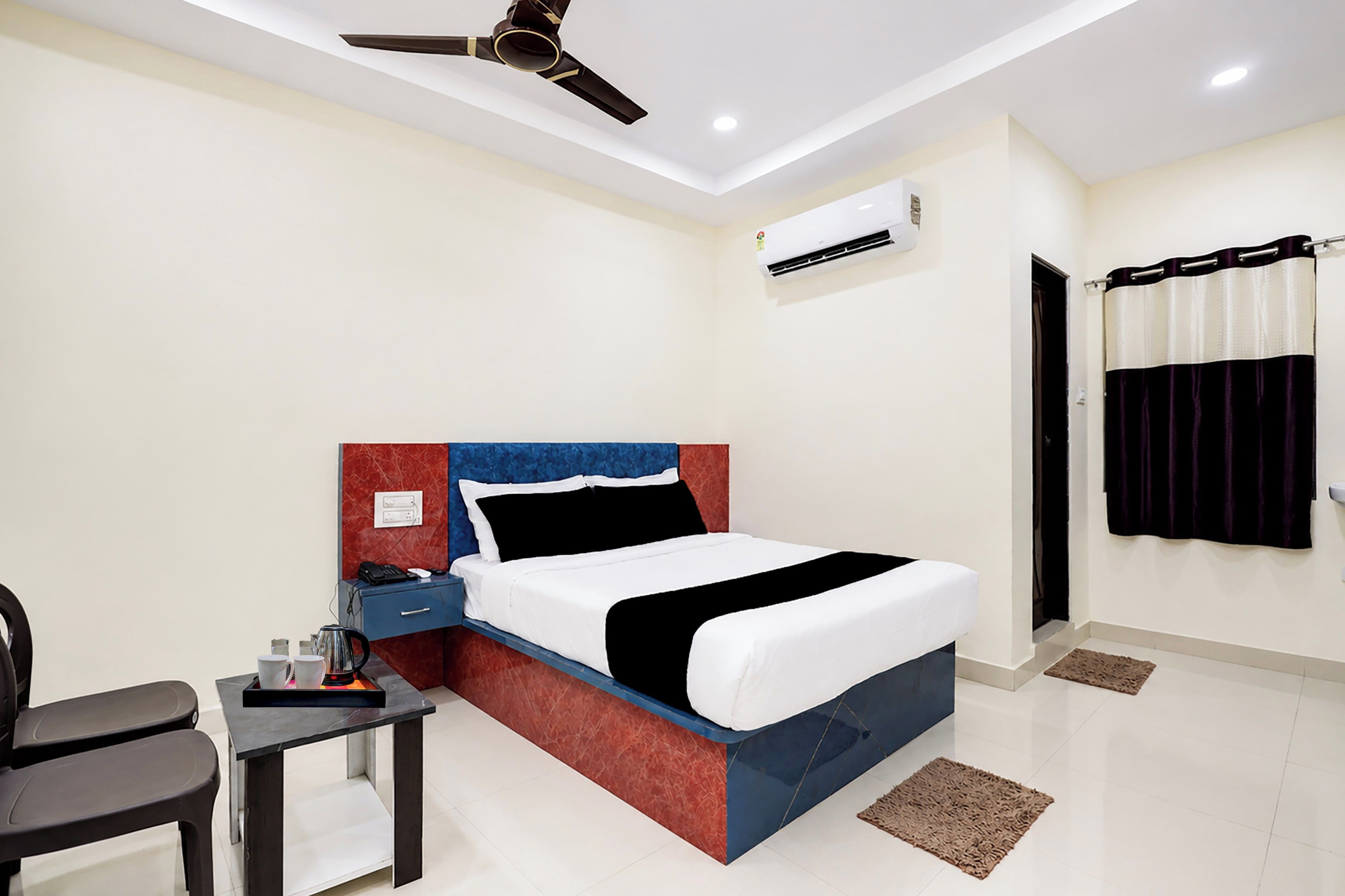 A hotel room with a bed, bedside table, chair, and ceiling fan.