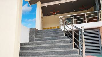 A staircase with metal railings leading to a landing with a ceiling fan.