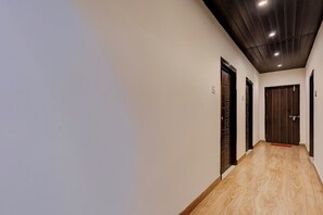 A hallway with wooden flooring, dark wooden doors, and a ceiling with recessed lighting. - Hotel O IT Hub Khammam (Khammam)
